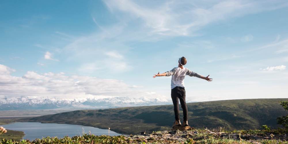 Person On Mountain With Increased Confidence After Using Physical Exercise To Treat Addiction