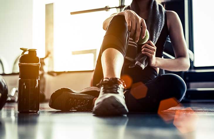 Woman Sitting On Floor After Exercising To Help With Alcohol Recovery