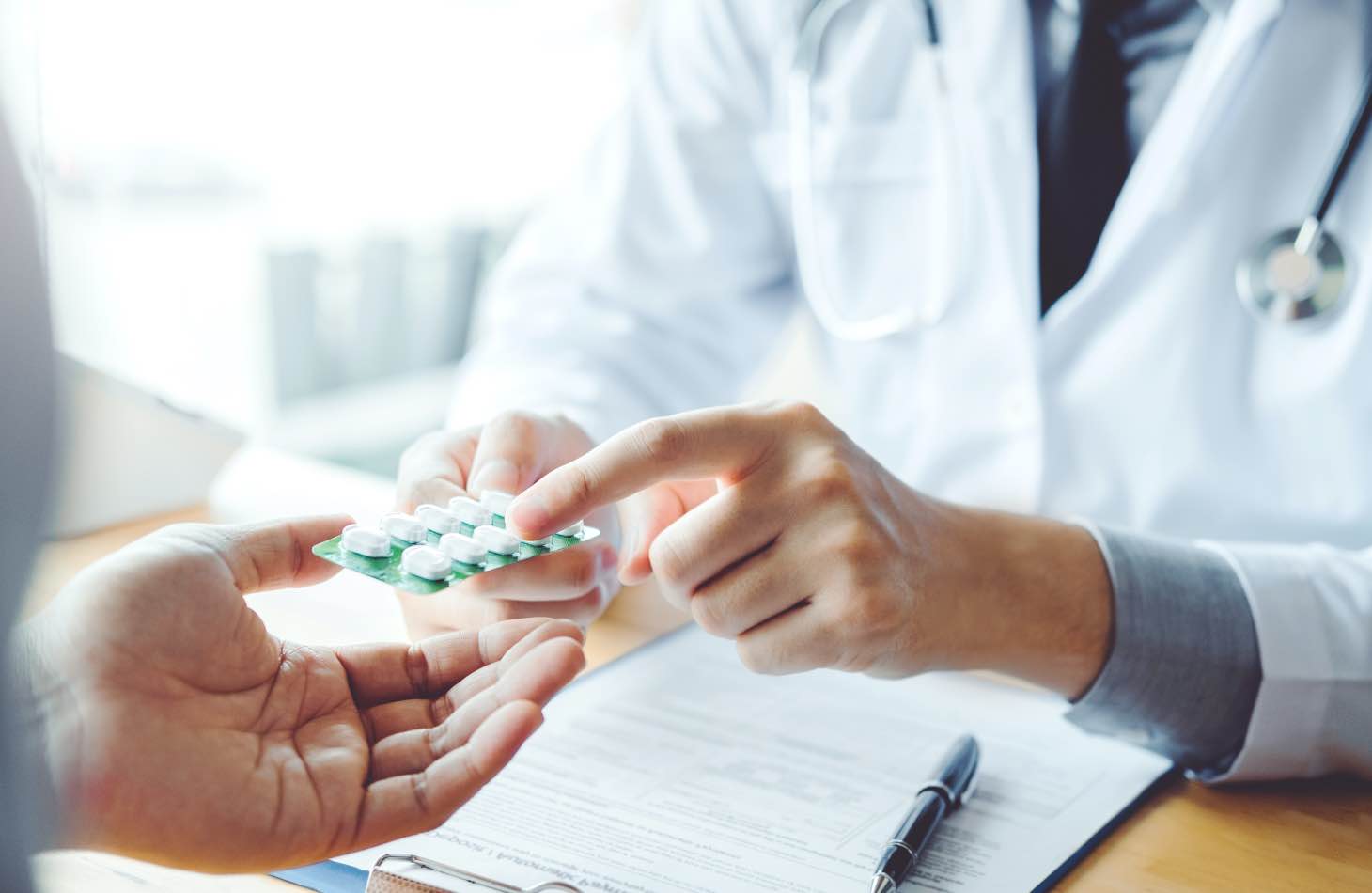 A Doctor Pointing To A Client's Pills, Explaining Medication Assisted Treatment