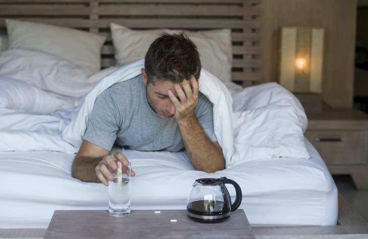 Man In Bed Exhibiting The Short Term Mental Effects Of Alcohol Abuse