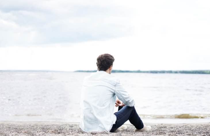 Person Sitting On Beach Focused On Long Term Sobriety From Alcohol Addiction