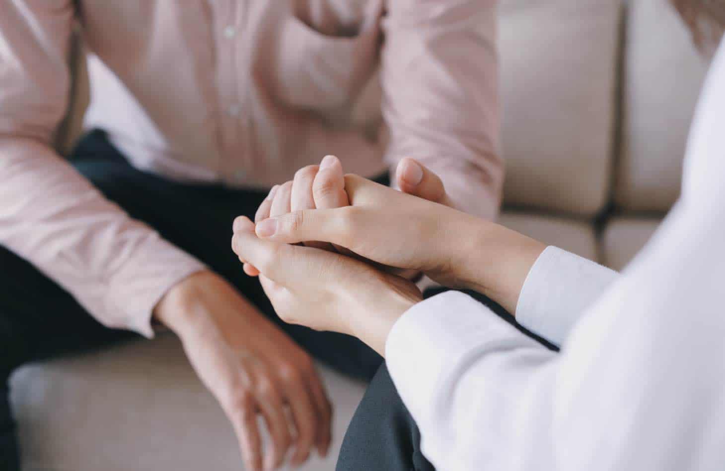 Therapist Holding Hand Of Client Dealing With Dual Diagnosis And Alcohol Addiction