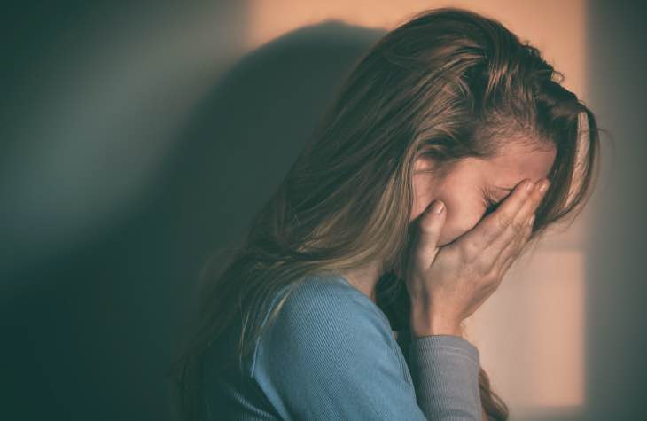 Woman With Hands Over Face As She Experiences Side Effects Of Alcohol Abuse On The Brain