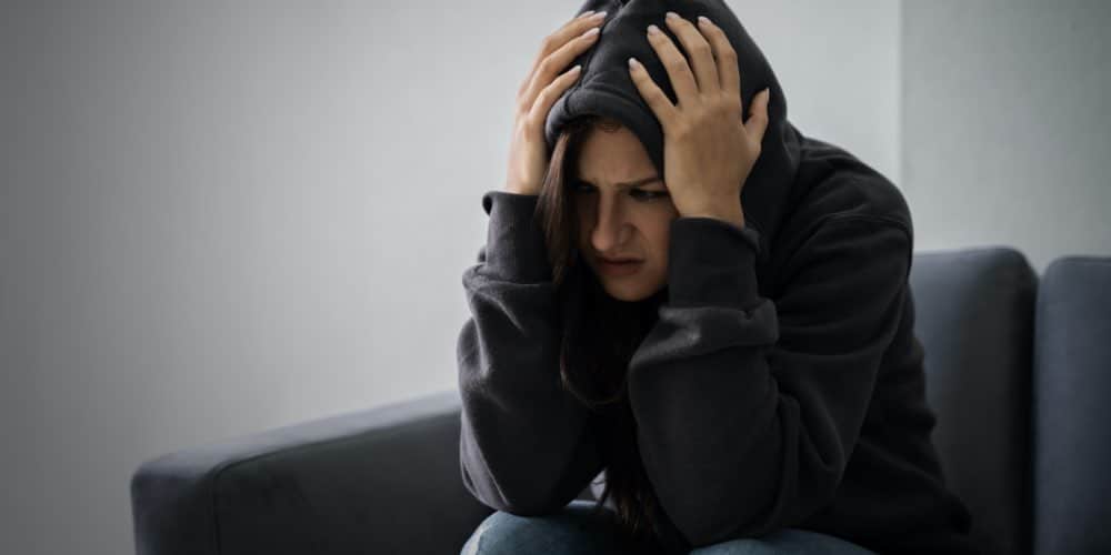 Woman With Hands On Head In Black Hoodie Struggling With Drug Dependence