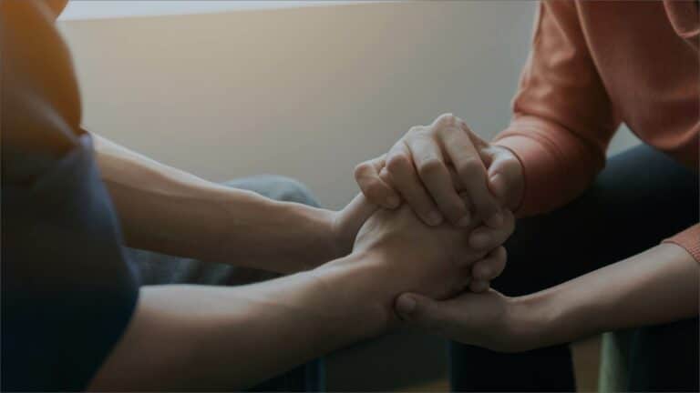 Two people holding hands discussing how to find the best rehab center