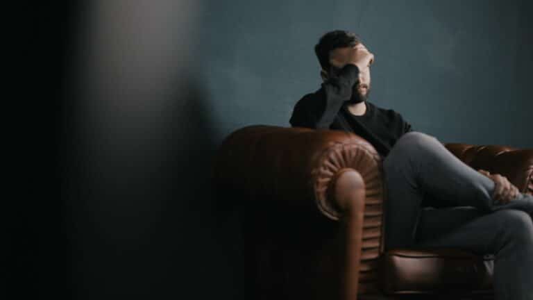 man sitting in chair struggling with an addiction to cocaine and hair loss