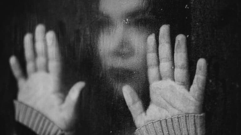 Woman with hands on glass seeking dual diagnosis recovery