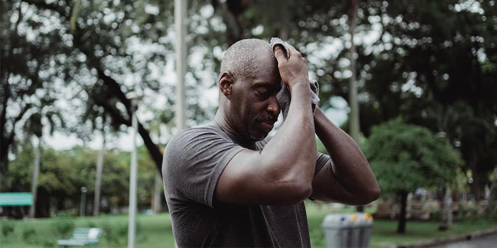 a man who is feeling dehydrated and wiping off his sweat due to intense exercising