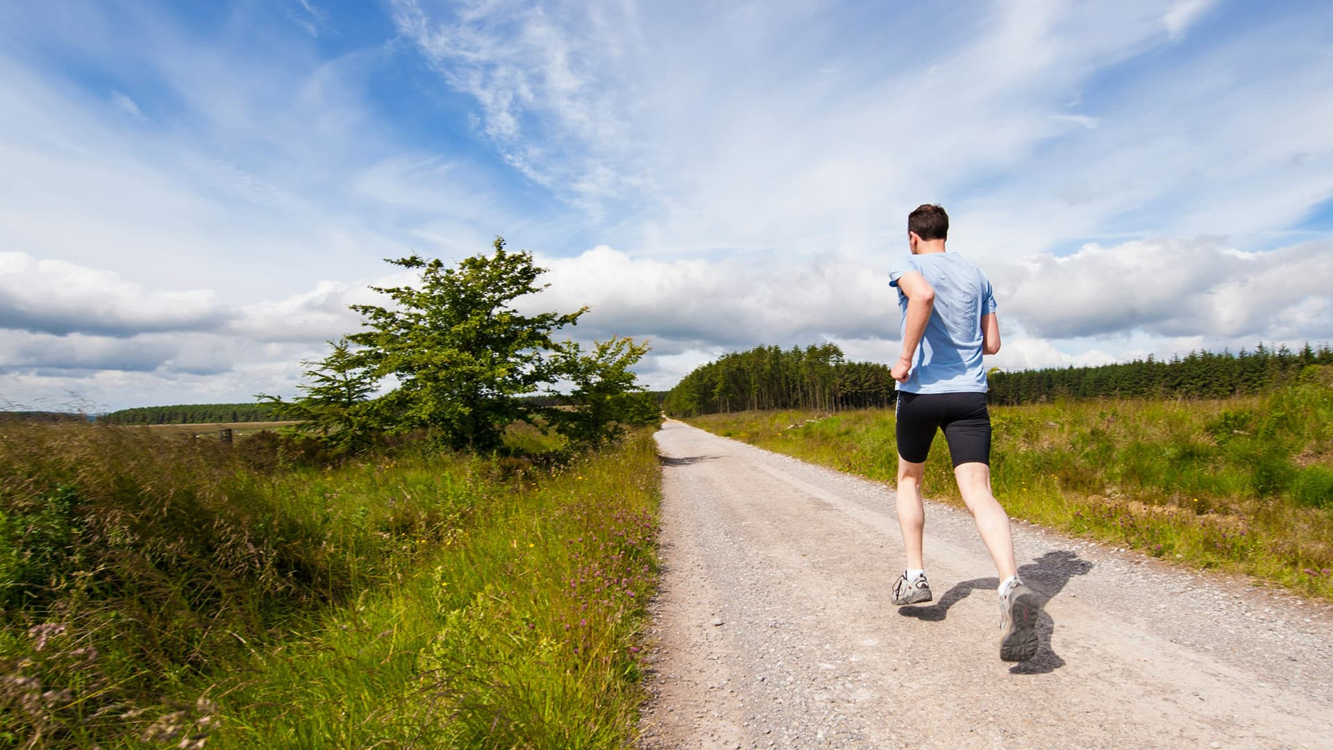 man running on road near grass field