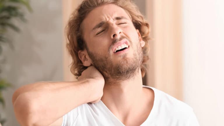 Young man suffering from neck pain at home