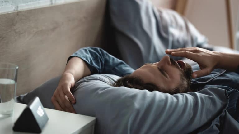 Young man yawning while lying on bed