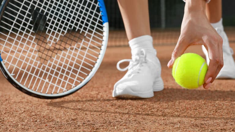 Young woman with tennis racket and ball at court