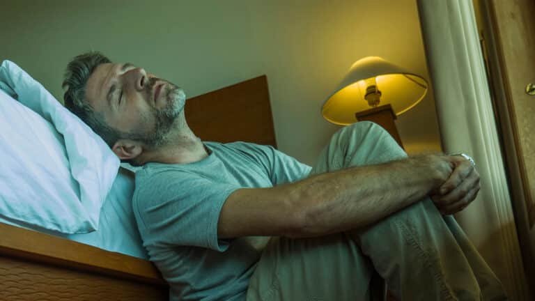 depressed and desperate man sitting on bedroom floor