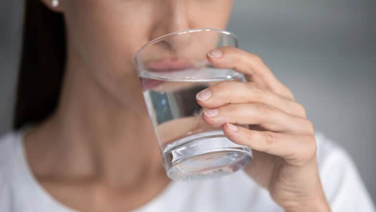 Young lady holding glass sipping fresh pure water