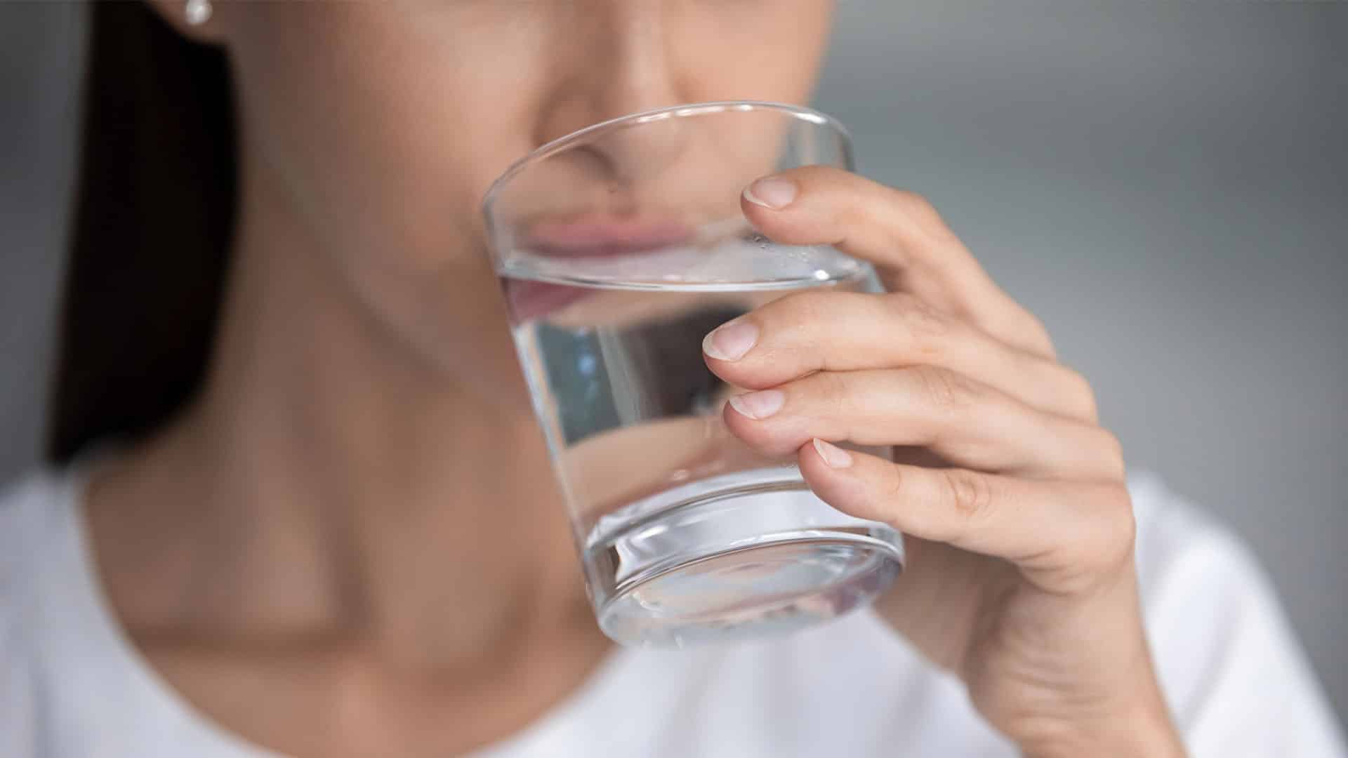 Young lady holding glass sipping fresh pure water