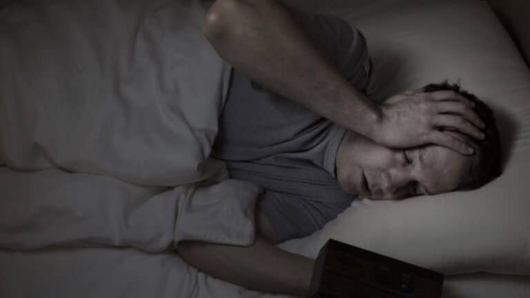 restless man in bed while trying to sleep