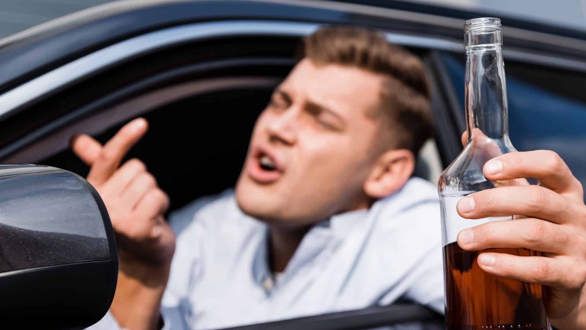 Drunk man with bottle of alcohol showing come here gesture while looking out car window