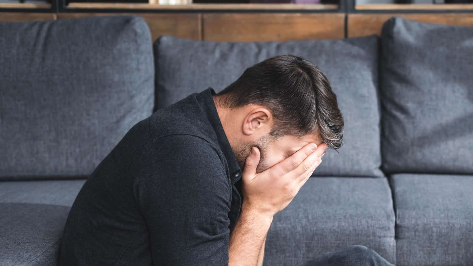 Side view of man with panic attack crying in apartment