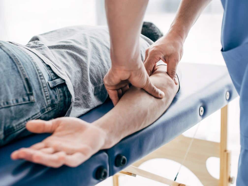 chiropractor massaging arm of patient