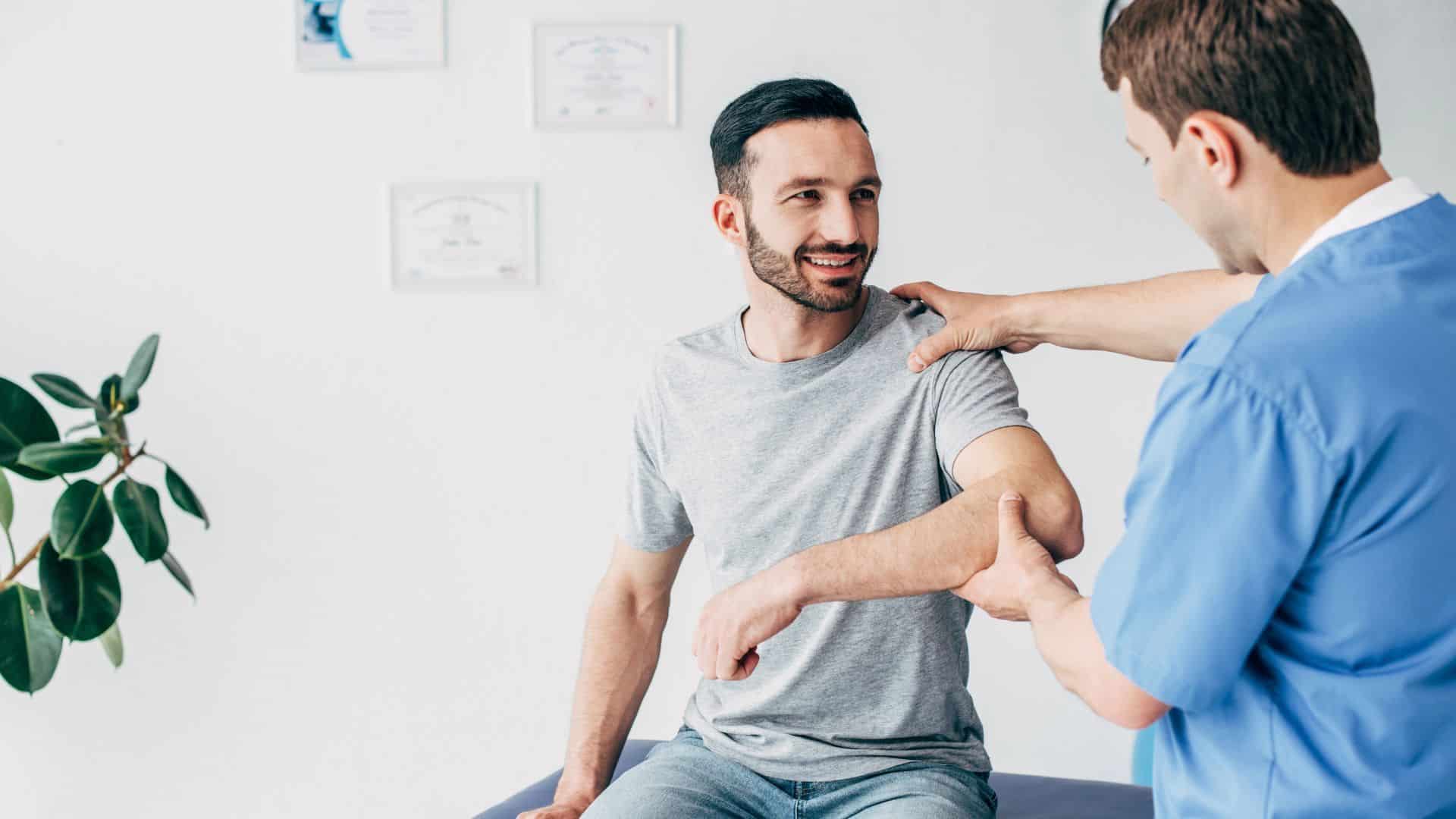 examining patient shoulder in massage cabinet at clinic