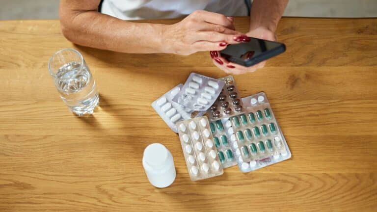 woman holding pills and glass of fresh water at home