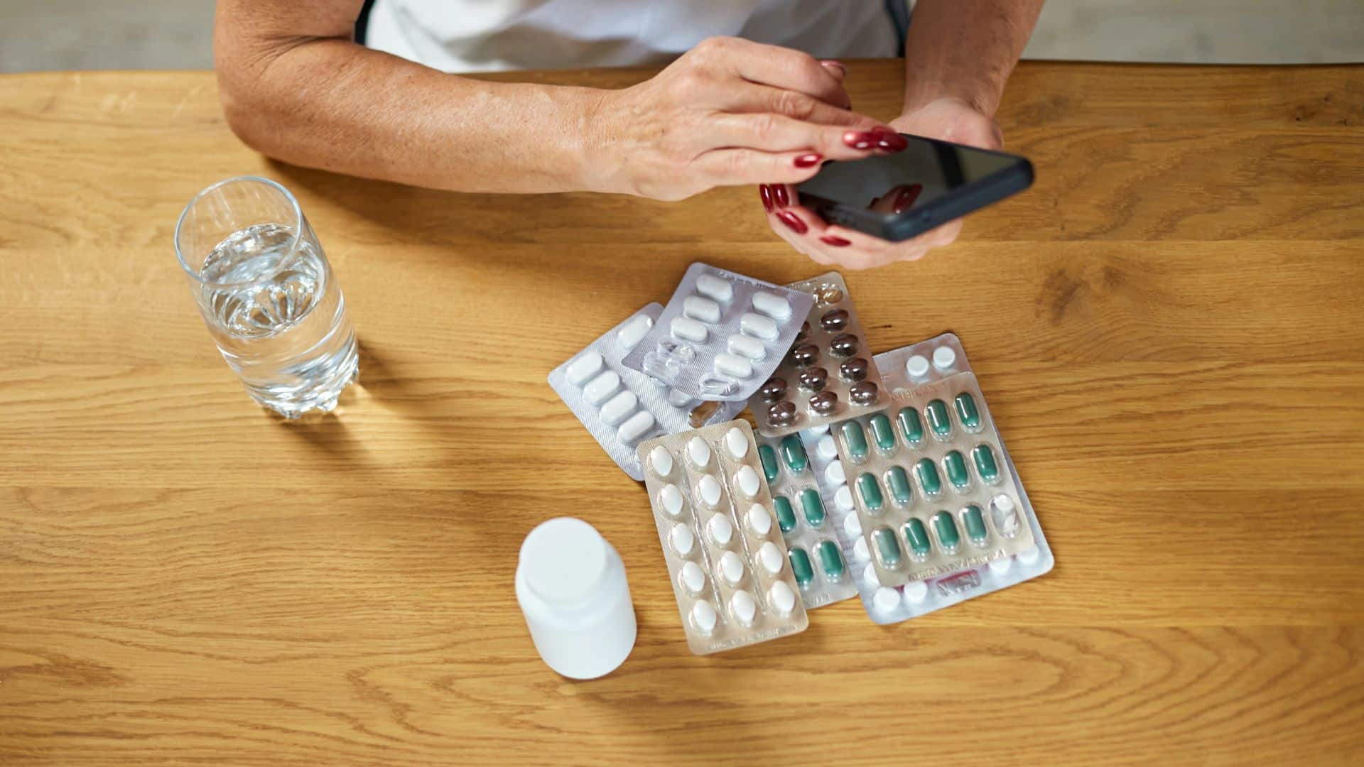 woman holding pills and glass of fresh water at home