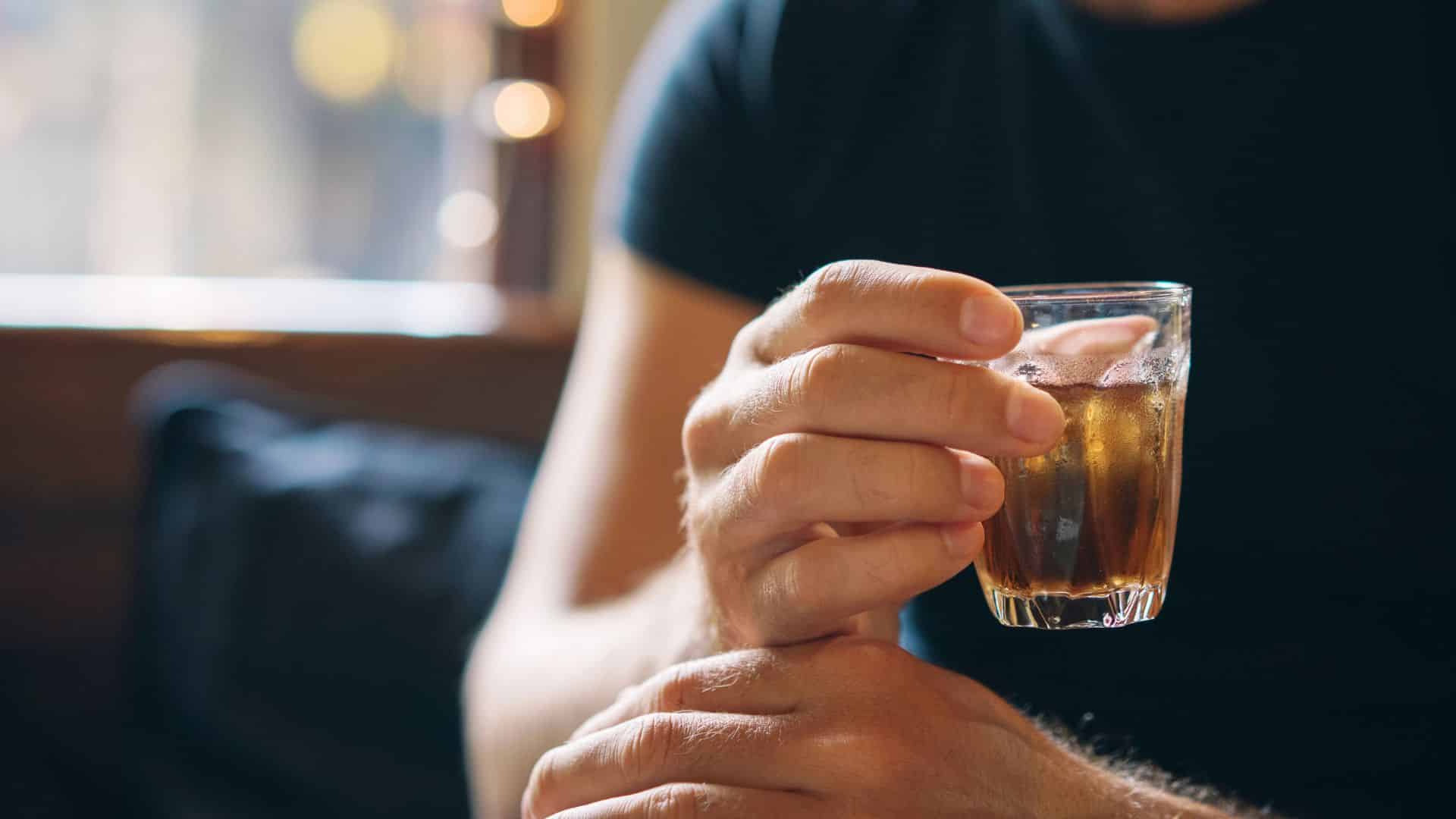 glass with an alcohol in the hand of a man
